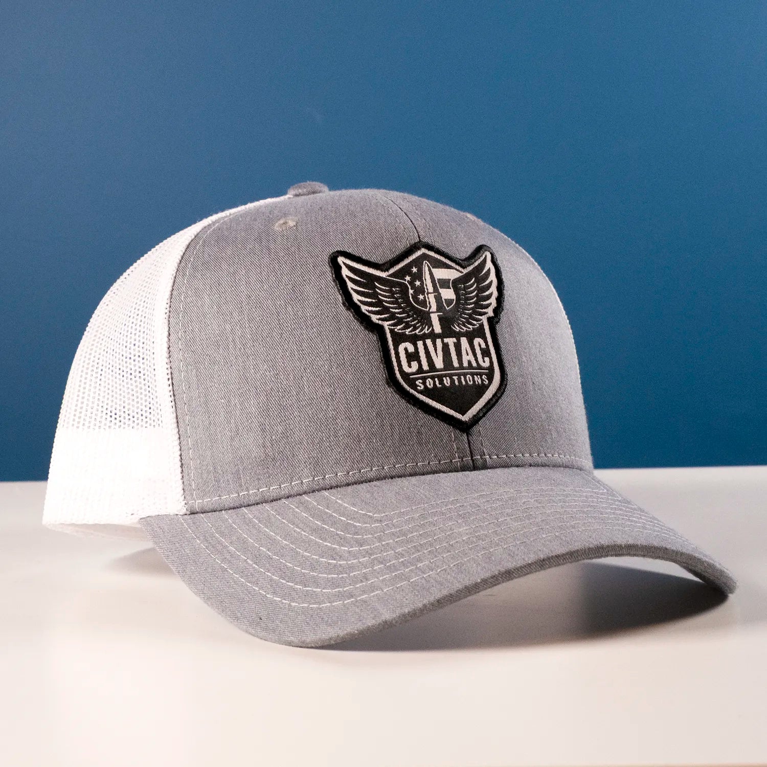 The Veteran grey and white trucker hat with a logo on a blue background